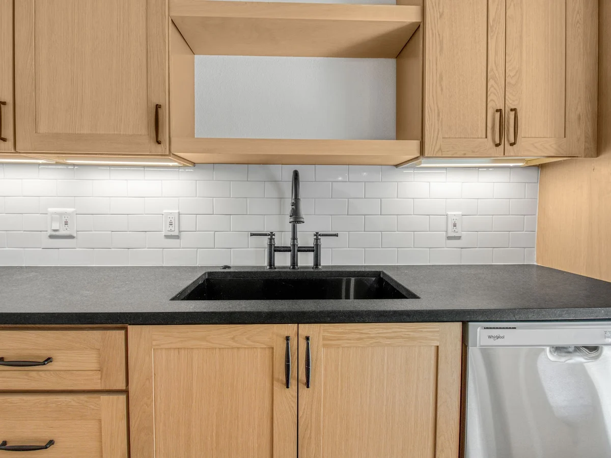 Completed Lantern kitchen with oak cabinetry, white subway tile backsplash, and a black quartz counter